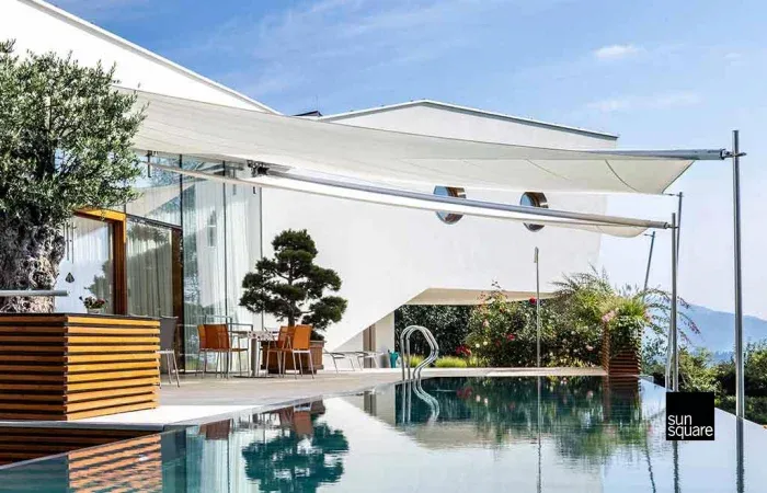 Zwei weiße Sonnensegel über einer eleganten Pool-Terrasse.