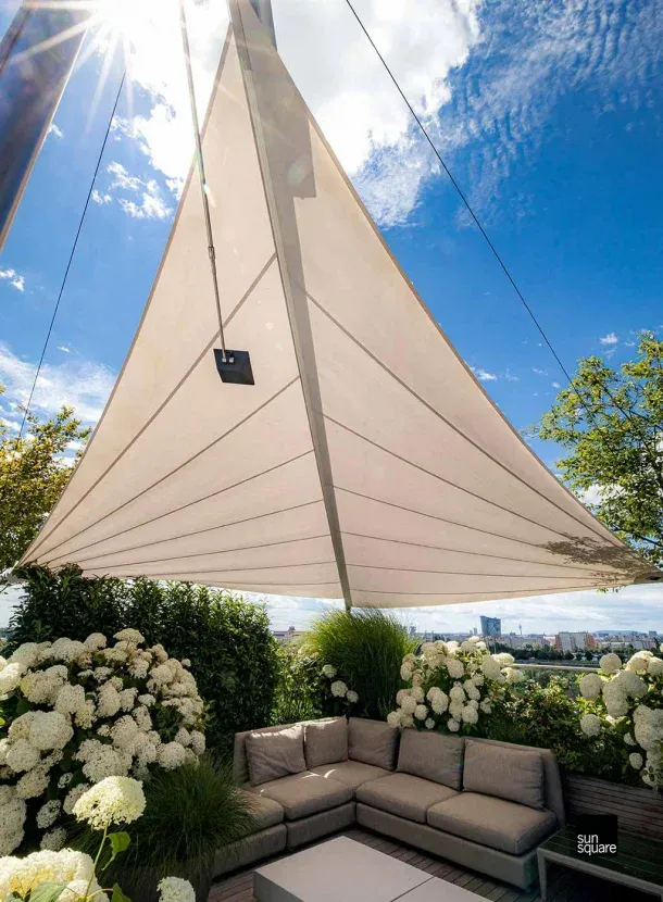 Dreieckiges Sonnensegel von unten fotografiert vor blauem Himmel.