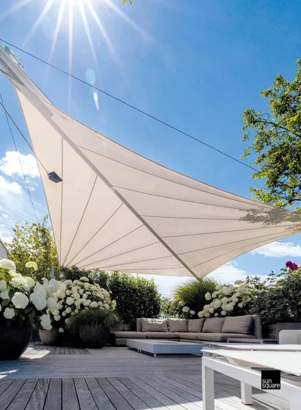 Gemütlicher Loungebereich unter einem weißen Sonnensegel mit Hortensien.