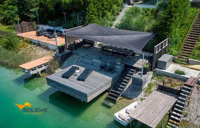 Modernes schwarzes Sonnensegel Fürstenfeldbruck über einer Seeterrasse mit Steg.